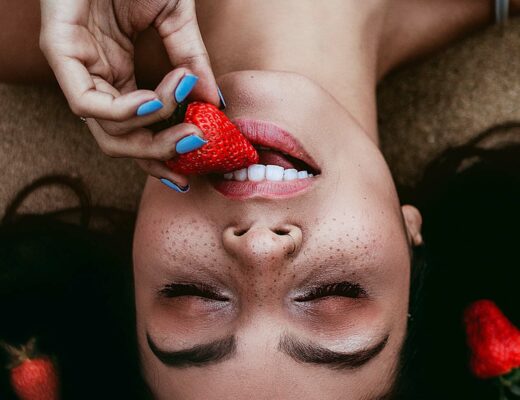 girl eating strawberry to get best vitamins for teeth and gums