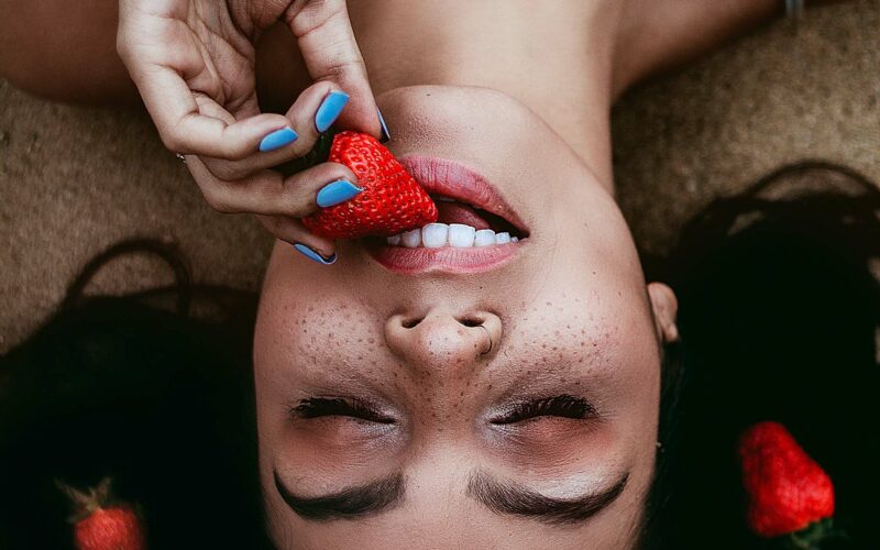 girl eating strawberry to get best vitamins for teeth and gums