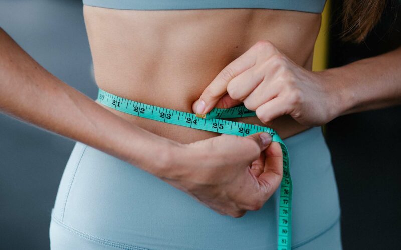 woman measuring waist to see how much weight you can lose in a month