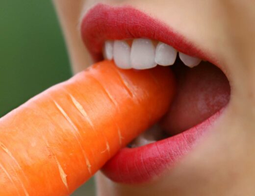 woman eating carrot to get vitamins for strong teeth