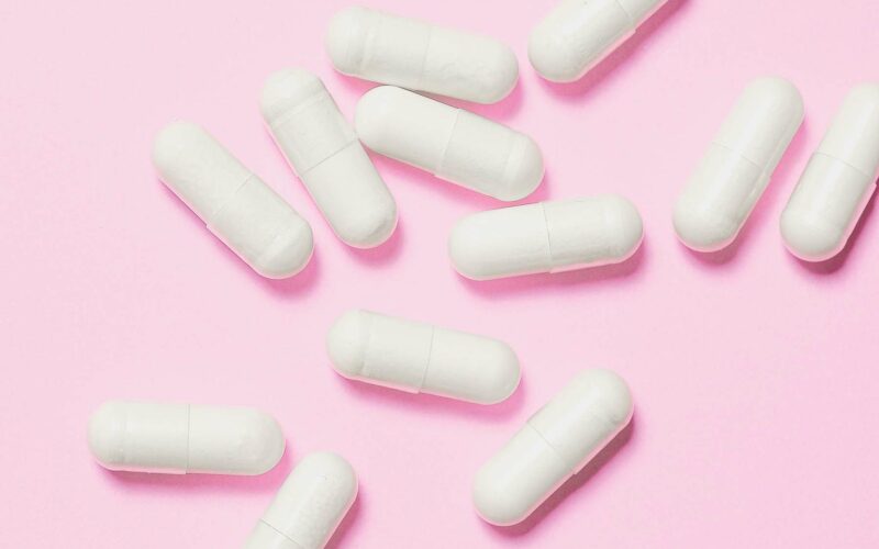 white vitamins for hearing on pink background